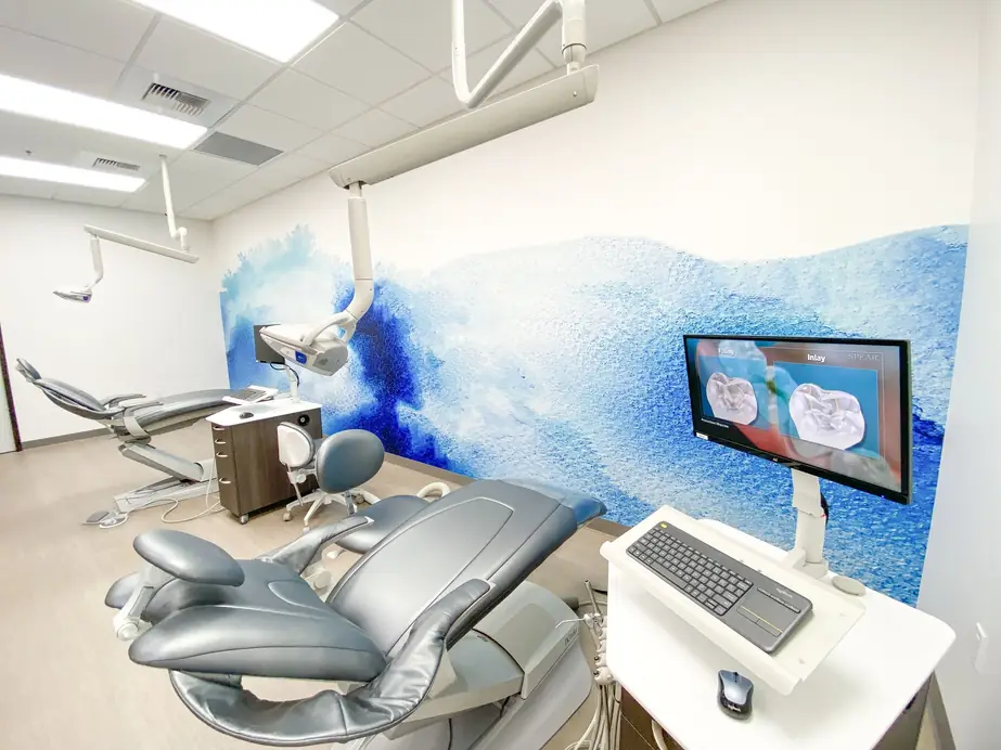Treatment room with grey dental chairs in front of a blue watercolour wall