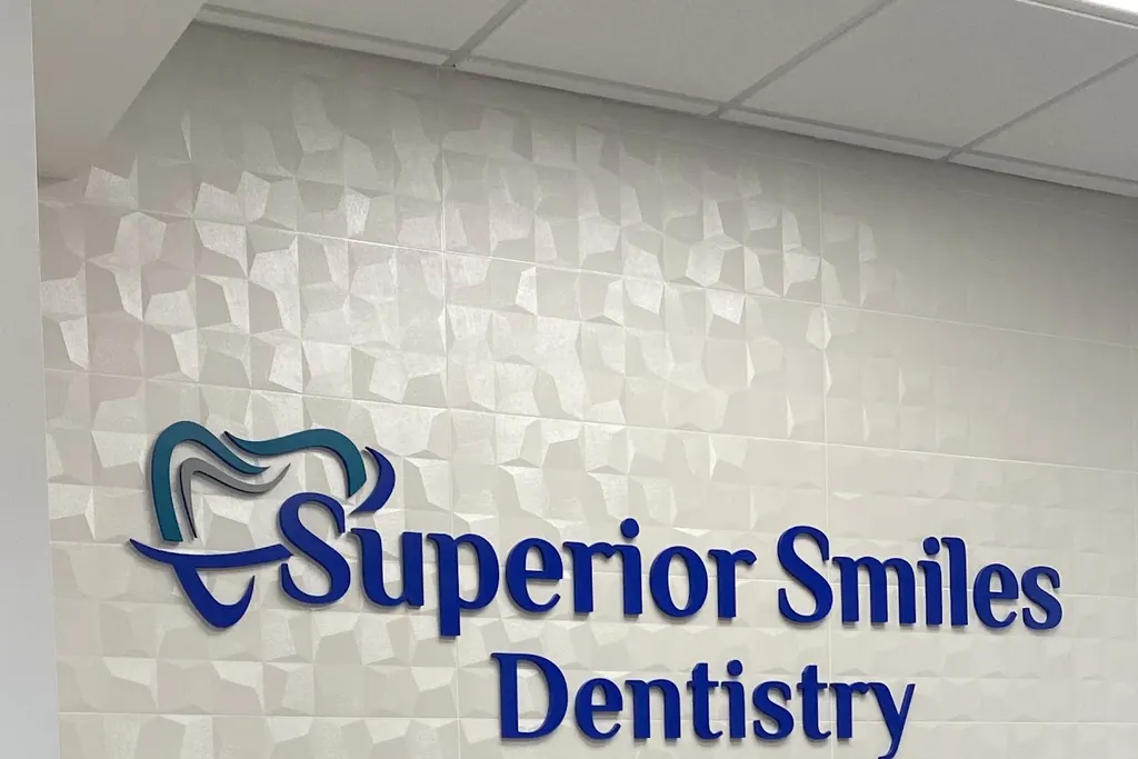 Superior Smiles Dentistry logo sign on the textured white wall behind the front desk