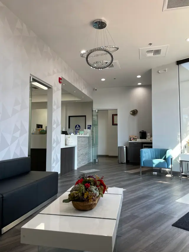 Waiting room with a crystal chandelier, grey sofa, white table and blue armchair